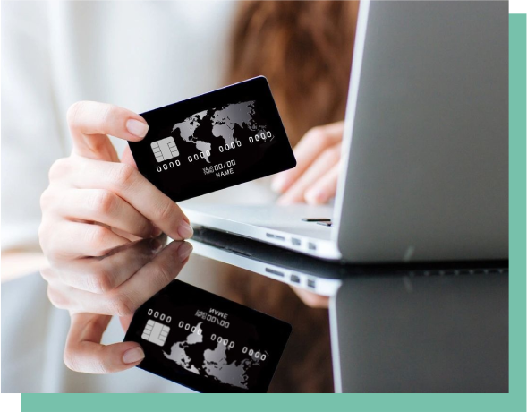 A person holding their credit card over the keyboard of a laptop.